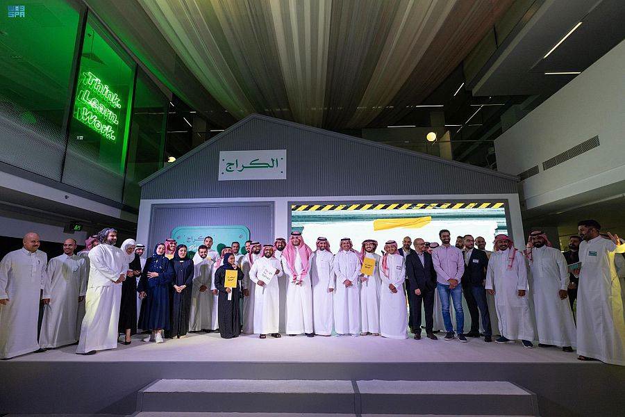 Participants and partners on stage in front of The Garage's house-shaped set, August 2022